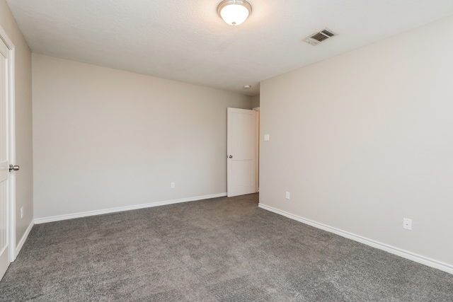 unfurnished room featuring a textured ceiling and dark colored carpet