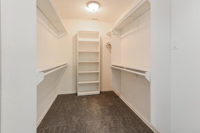 spacious closet featuring dark carpet