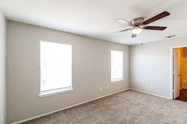 carpeted empty room featuring a wealth of natural light and ceiling fan