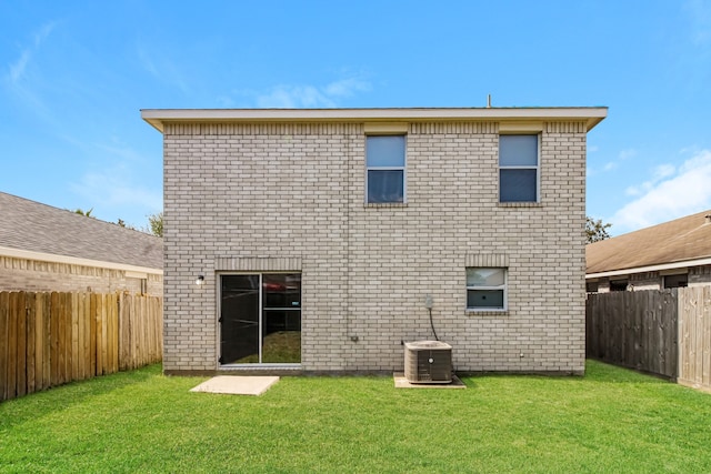 back of house with central AC unit and a yard