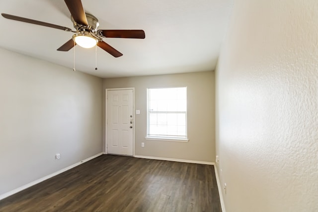 empty room featuring dark wood-type flooring and ceiling fan