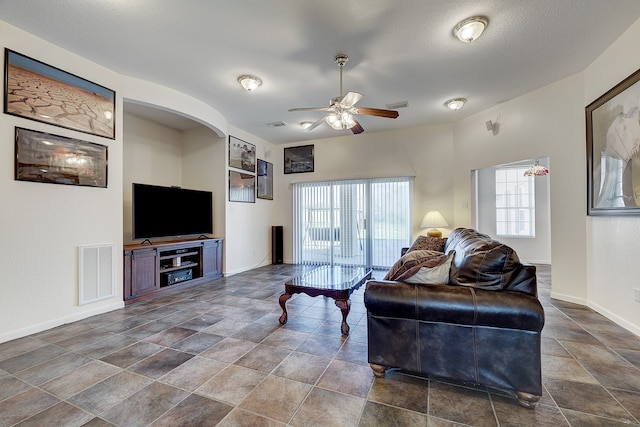 living room featuring ceiling fan and a textured ceiling