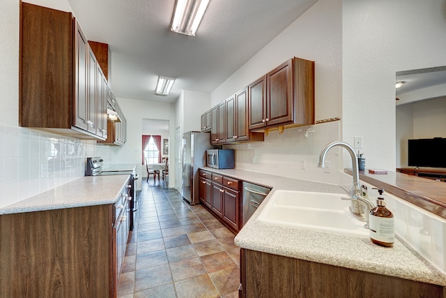 kitchen with a textured ceiling, decorative backsplash, stainless steel appliances, and sink