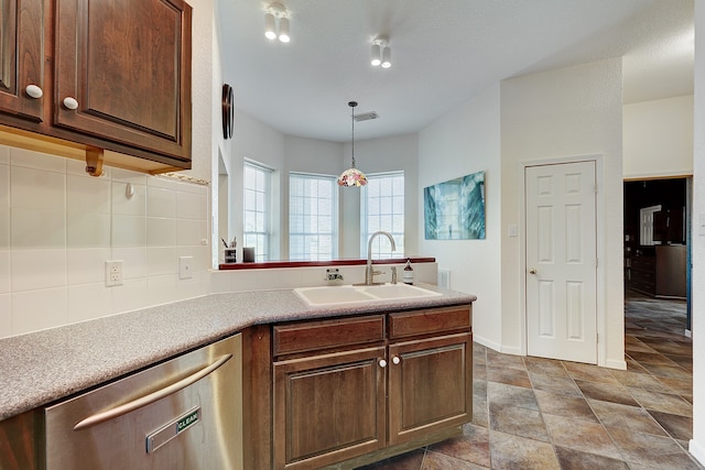 kitchen featuring stainless steel dishwasher, hanging light fixtures, sink, and backsplash