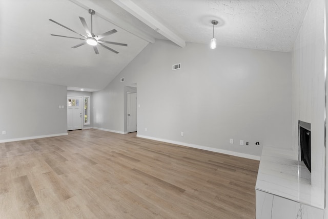 unfurnished living room with vaulted ceiling with beams, ceiling fan, a textured ceiling, and light hardwood / wood-style flooring