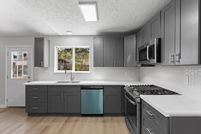 kitchen featuring gray cabinetry, a wealth of natural light, light hardwood / wood-style flooring, and appliances with stainless steel finishes