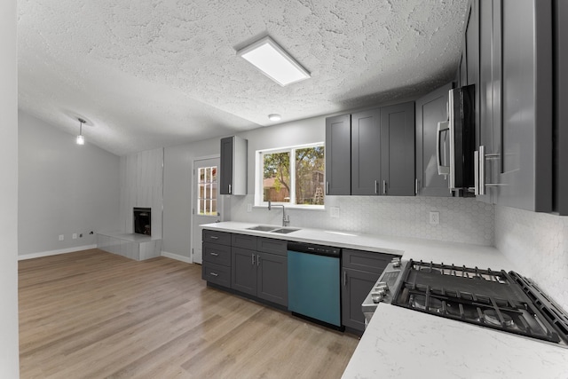 kitchen with sink, light hardwood / wood-style flooring, gray cabinets, a textured ceiling, and stainless steel appliances