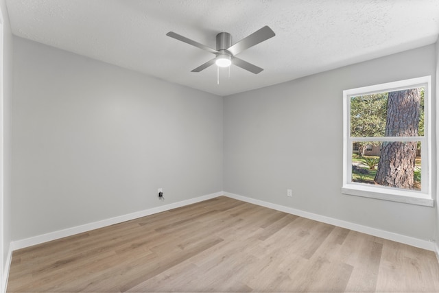 spare room featuring ceiling fan, light wood-type flooring, and a textured ceiling