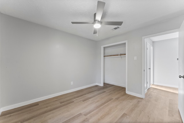 unfurnished bedroom featuring ceiling fan, a closet, a textured ceiling, and light hardwood / wood-style flooring