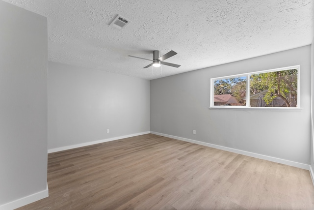 empty room with ceiling fan, wood-type flooring, and a textured ceiling