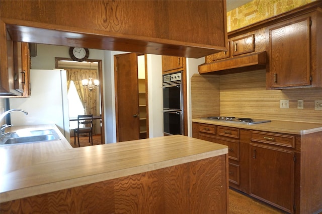 kitchen with stainless steel gas stovetop, backsplash, sink, black double oven, and kitchen peninsula