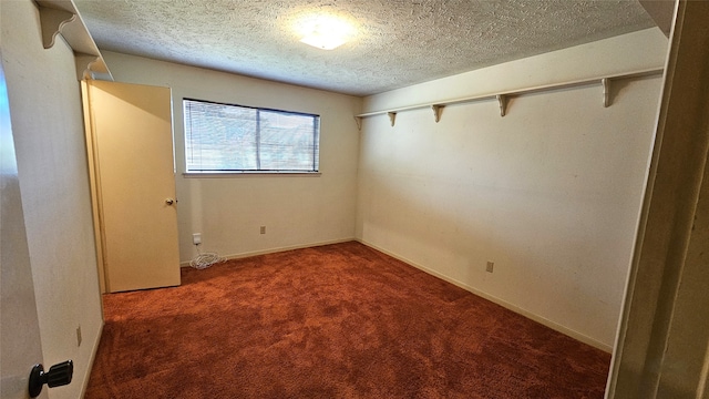 unfurnished room featuring a textured ceiling and dark carpet