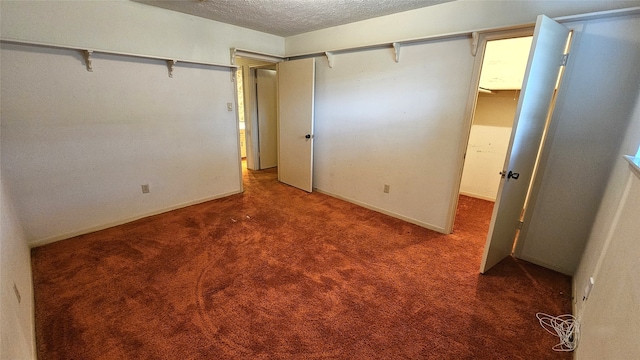 unfurnished bedroom featuring a textured ceiling, dark carpet, and a closet