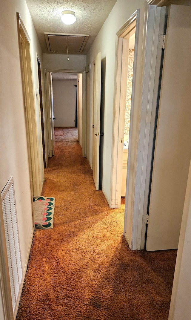 hall with light colored carpet and a textured ceiling