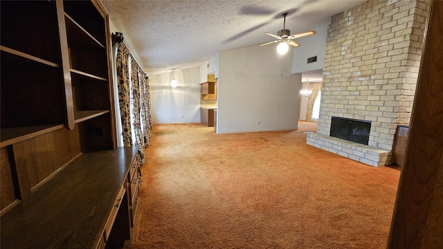 unfurnished living room with ceiling fan, vaulted ceiling, a textured ceiling, a fireplace, and carpet