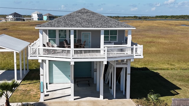 coastal home with a wooden deck, a front yard, and a patio area