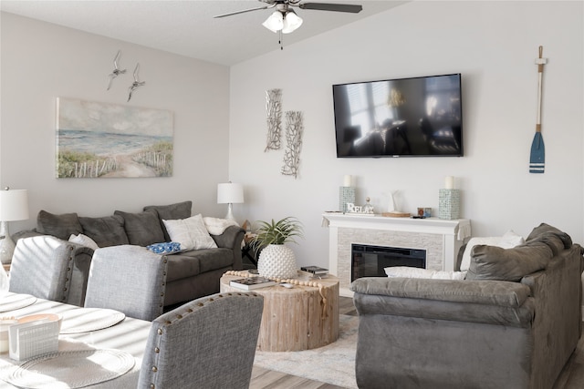 living room with hardwood / wood-style floors, lofted ceiling, a stone fireplace, and ceiling fan