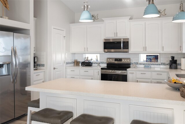 1286 Lagoon Dr, Crystal Beach, TX 77650 - kitchen with appliances with stainless steel finishes, decorative backsplash, white cabinetry, and a breakfast bar