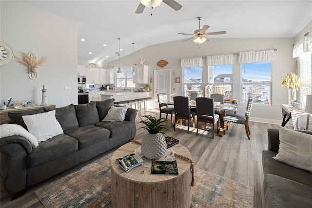 living room featuring light wood-type flooring, ceiling fan, and vaulted ceiling