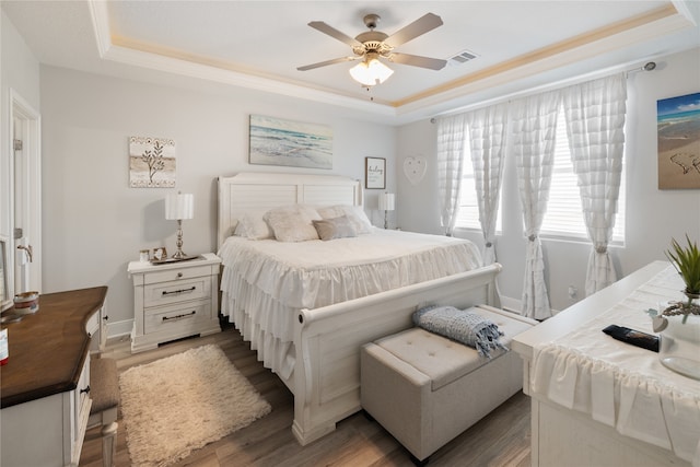 bedroom featuring dark hardwood / wood-style floors, ceiling fan, and a raised ceiling