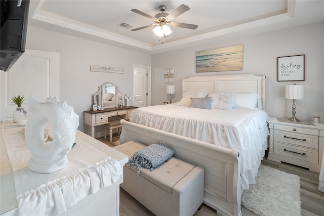 bedroom featuring hardwood / wood-style floors, ceiling fan, and a raised ceiling