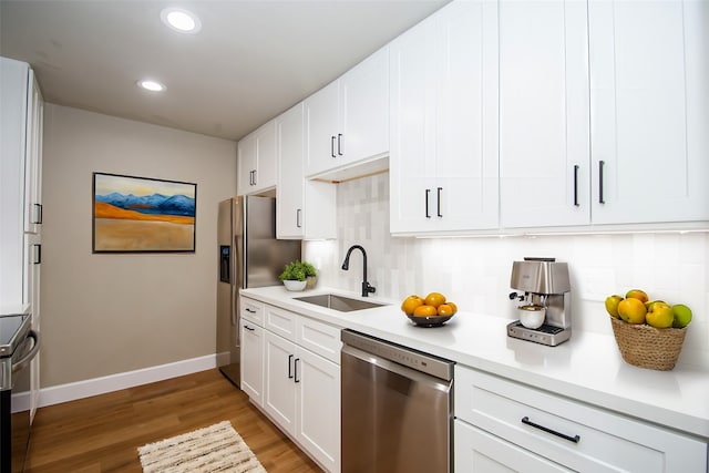 kitchen featuring white cabinetry, sink, appliances with stainless steel finishes, backsplash, and light wood-type flooring