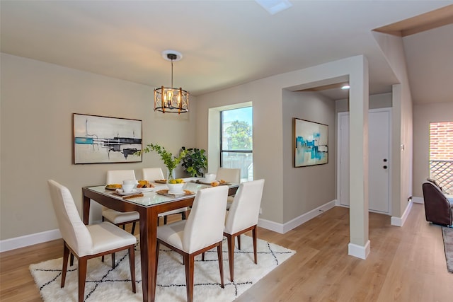 dining area with light wood-type flooring and a notable chandelier