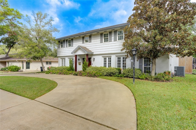 colonial-style house featuring central air condition unit and a front yard