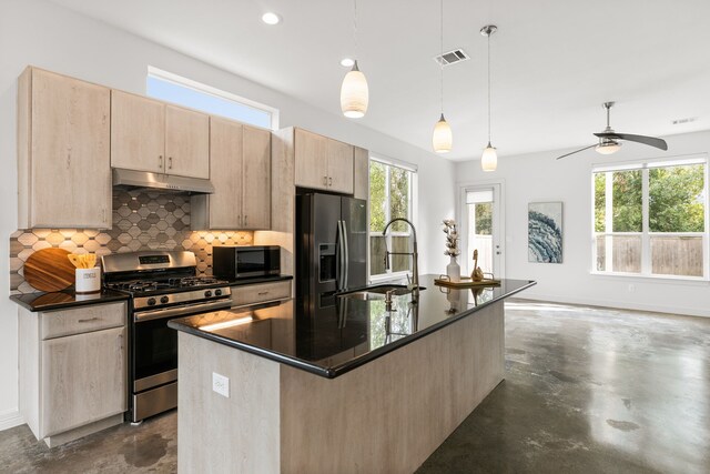 kitchen featuring stainless steel appliances, backsplash, decorative light fixtures, sink, and a kitchen island with sink