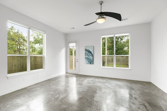 empty room featuring concrete flooring, ceiling fan, and plenty of natural light