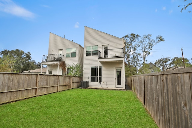 back of house featuring central air condition unit, a yard, and a balcony