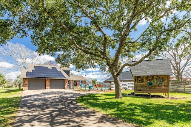 view of front of home with solar panels, a garage, a playground, and a front yard