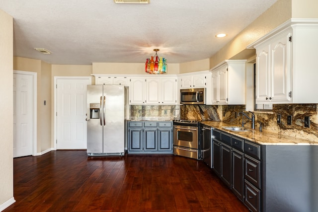 kitchen featuring stainless steel appliances, dark wood-type flooring, sink, dark stone countertops, and white cabinets