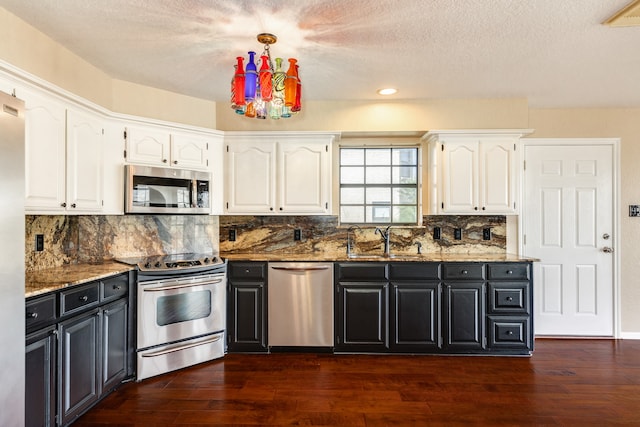 kitchen featuring dark stone counters, white cabinets, sink, dark hardwood / wood-style flooring, and stainless steel appliances