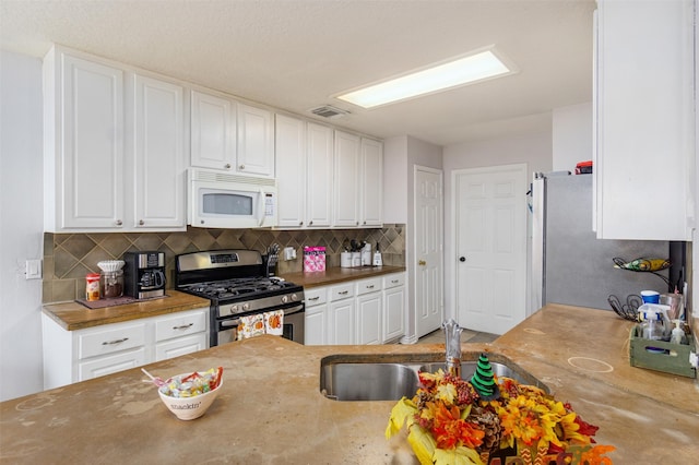 kitchen with white cabinetry, tasteful backsplash, and white appliances