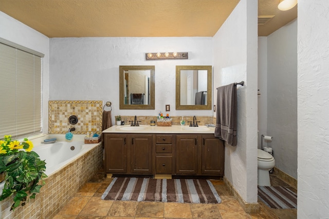 bathroom with toilet, vanity, a relaxing tiled tub, and a textured ceiling