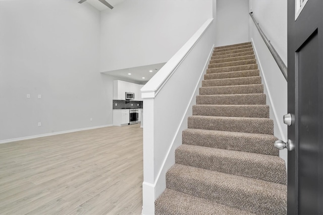 stairway featuring a towering ceiling and hardwood / wood-style flooring