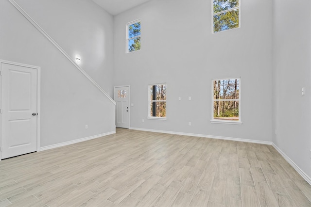 unfurnished living room featuring light hardwood / wood-style floors and a high ceiling