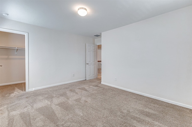 unfurnished bedroom featuring light colored carpet, a closet, and a walk in closet