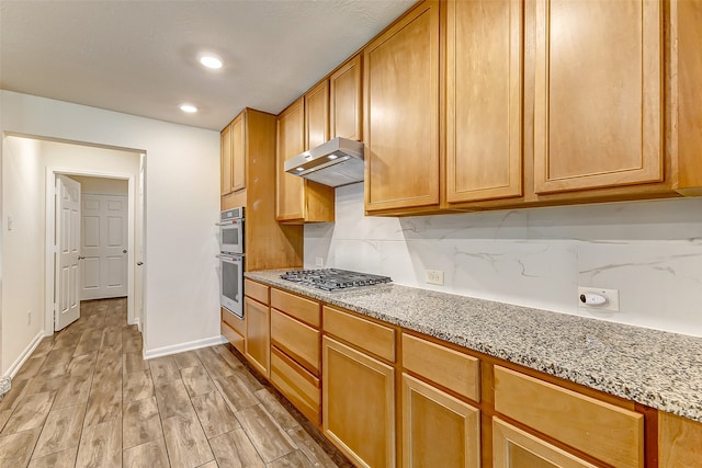 kitchen featuring light hardwood / wood-style floors, light stone countertops, appliances with stainless steel finishes, and tasteful backsplash