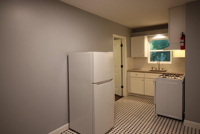 kitchen with sink, white cabinets, stove, white fridge, and decorative backsplash