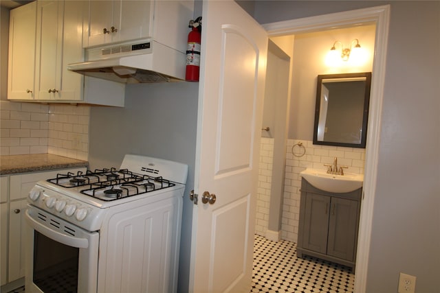 kitchen with gas range gas stove, decorative backsplash, light stone countertops, and sink