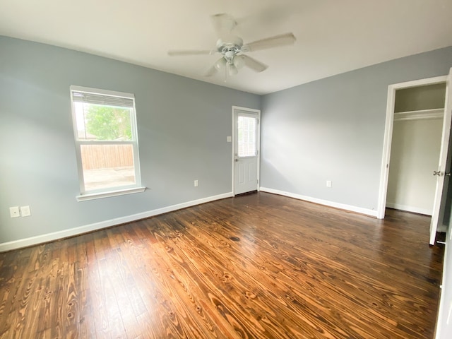 spare room featuring dark wood-type flooring, ceiling fan, and a healthy amount of sunlight