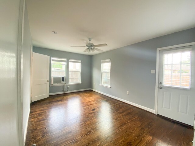 spare room with dark wood-type flooring, ceiling fan, cooling unit, and a healthy amount of sunlight