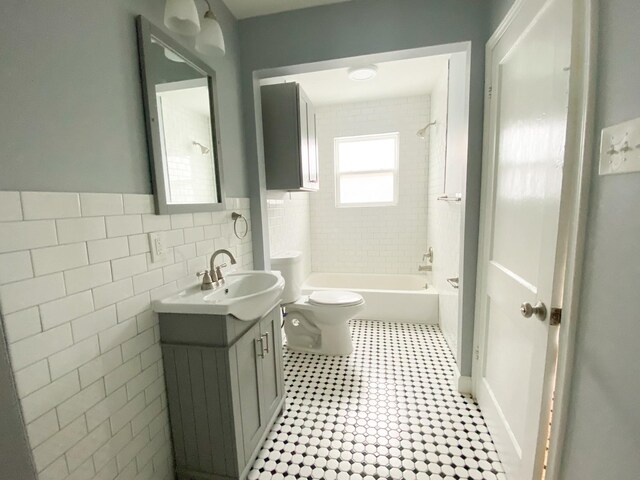 full bathroom with toilet, vanity, tile walls, and tiled shower / bath