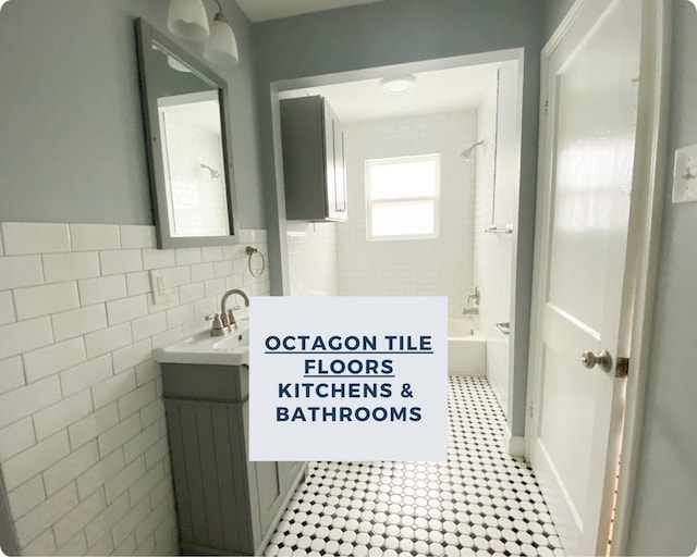 bathroom featuring vanity, tiled shower / bath, and tile walls