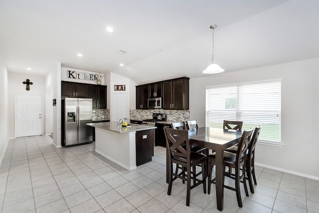 kitchen with stainless steel appliances, light tile patterned floors, decorative light fixtures, lofted ceiling, and a center island