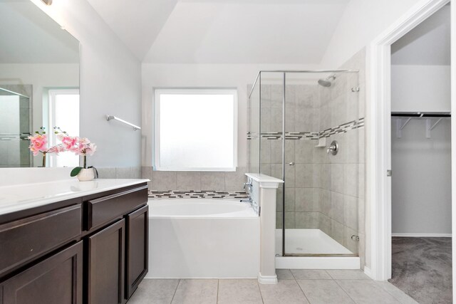 bathroom featuring vanity, independent shower and bath, tile patterned flooring, and lofted ceiling