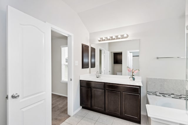 bathroom with toilet, vanity, lofted ceiling, and tile patterned floors