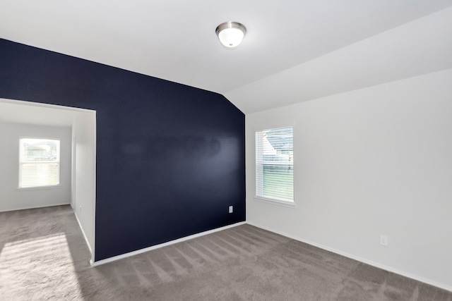 carpeted empty room featuring lofted ceiling